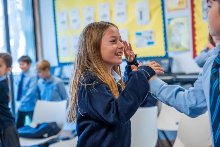 A student smiling with hands up