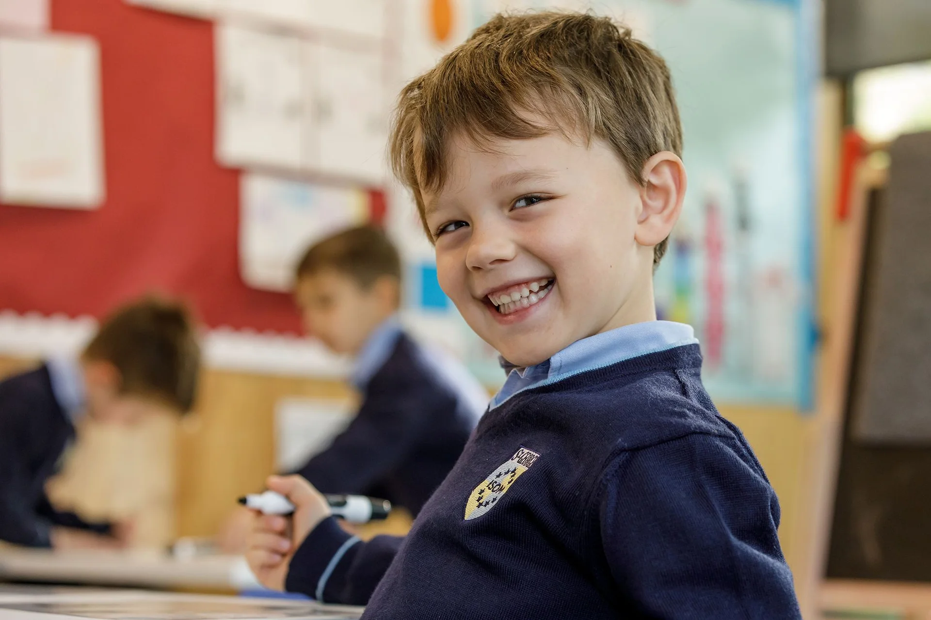 Pre school student holding a pen and smiling