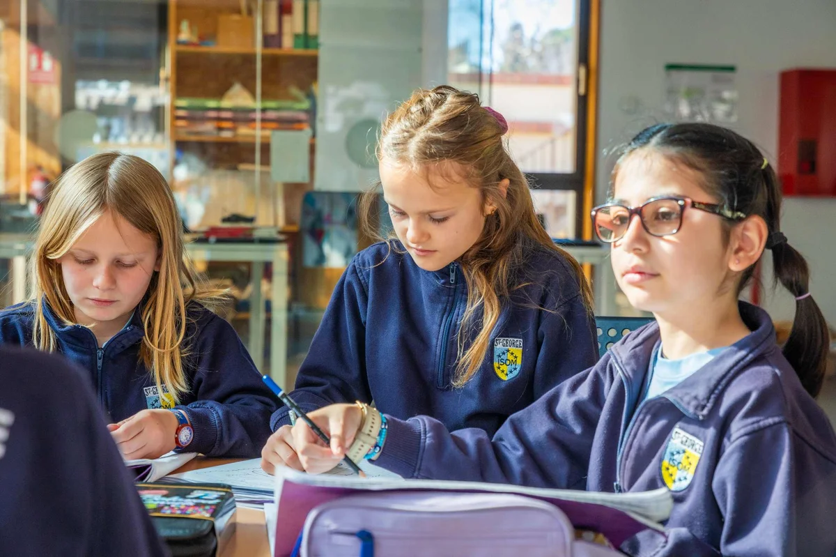 Three students in the classroom writing 