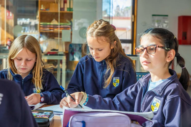 Three students in the classroom writing 
