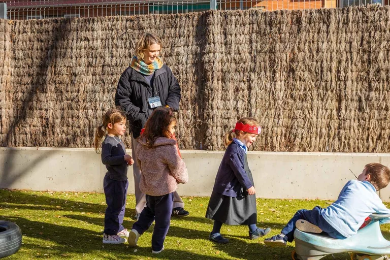 Teacher in the schoolyard with three little students