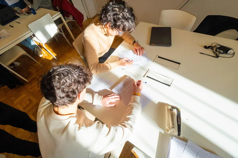 Two students writing a paper in the classroom